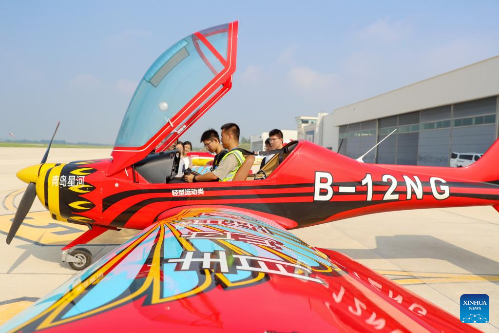 Seorang juruterbang memberi arahan kepada pelajar yang sedang mempelajari panel instrumen untuk menerbangkan pesawat di taman industri penerbangan am di Laixi, Qingdao, Provinsi Shandong di timur China pada 24 Ogos 2025. (Xinhua/Zhang Jingang)