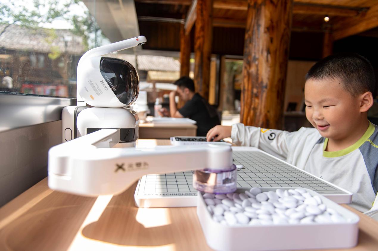 Seorang kanak-kanak bermain Go dengan robot yang dikuasakan AI di sebuah tapak pelancong di kaunti Congjiang, Provinsi Guizhou, barat daya China pada 9 Ogos 2025. (Foto oleh Wu Dejun)