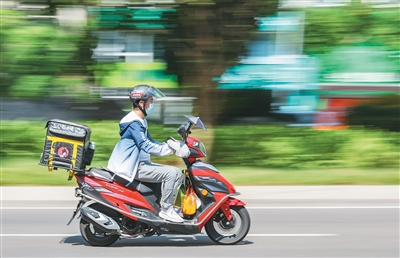 Seorang penghantar makanan sedang dalam perjalanan menghantar bungkusan di daerah Yubei, Perbandaran Chongqing di barat daya China pada 1 Oktober 2025. (Xinhua/Huang Wei) 2.	Foto penghantar memu