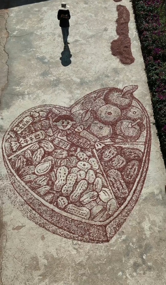 Tangkap layar video ini menunjukkan sebuah lukisan oleh Ning Si menggunakan isi jagung merah di kampung Xuanhe, kaunti autonomi Yi, Hani dan Lahu Zhenyuan, bandar Pu’er, provinsi Yunnan, barat daya China.