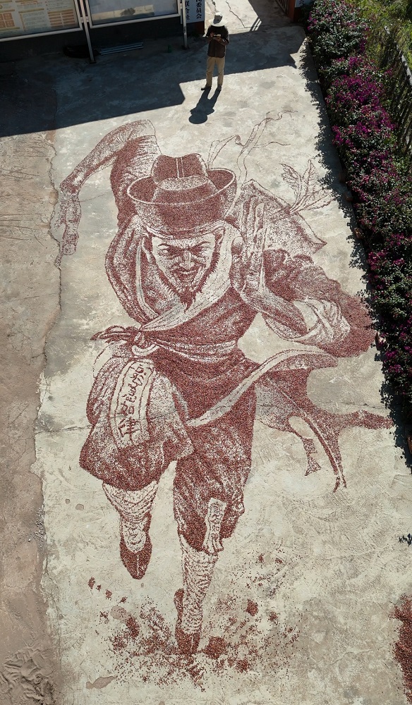 Tangkap layar video ini menunjukkan sebuah lukisan oleh Ning Si menggunakan isi jagung merah di kampung Xuanhe, kaunti autonomi Yi, Hani dan Lahu Zhenyuan, bandar Pu’er, provinsi Yunnan, barat daya China.