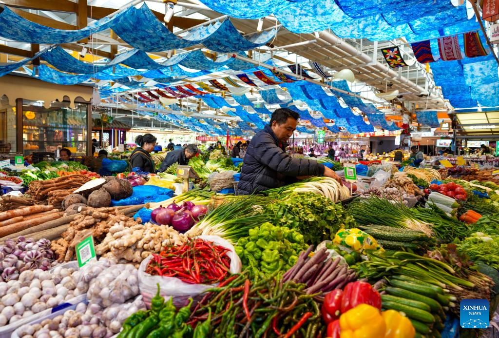 Seorang penjual menyusun sayur-sayuran di pasar tani Zhuanxin Daguan di Kunming, provinsi Yunnan, barat daya China, 27 Januari 2026. (Xinhua/Chen Xinbo)