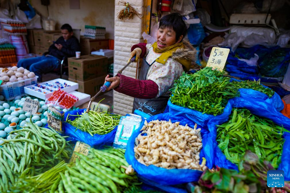Seorang penjual menyembur air pada sayur supaya kekal segar di pasar tani Zhuanxin Daguan di Kunming, provinsi Yunnan, barat daya China, 27 Januari 2026. (Xinhua/Chen Xinbo)