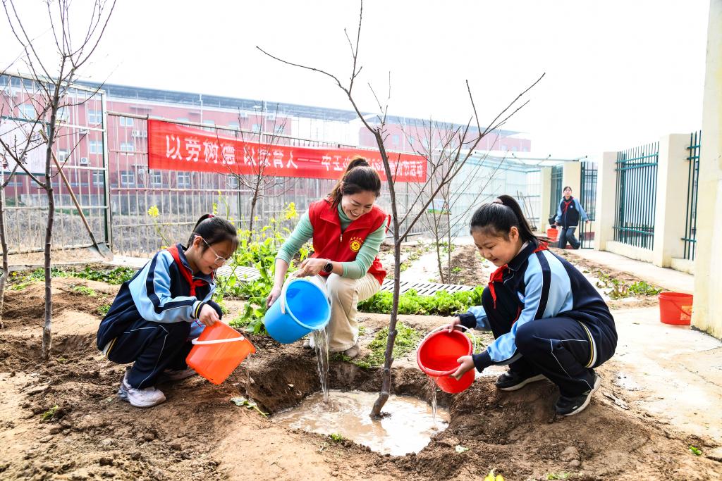 Murid-murid mengambil bahagian dalam acara menanam pokok bersama guru dan sukarelawan di sebuah sekolah rendah di Wuhan, provinsi Hubei, tengah China, 11 Mac 2026. (Foto oleh Zhao Jun/Xinhua)