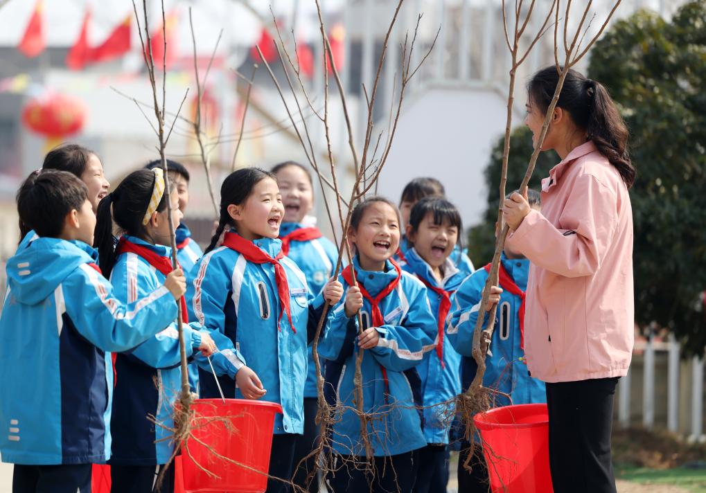 Murid-murid mengambil bahagian dalam acara menanam pokok bersama guru dan sukarelawan di sebuah sekolah rendah di Wuhan, provinsi Hubei, tengah China, 11 Mac 2026. (Foto oleh Zhao Jun/Xinhua)