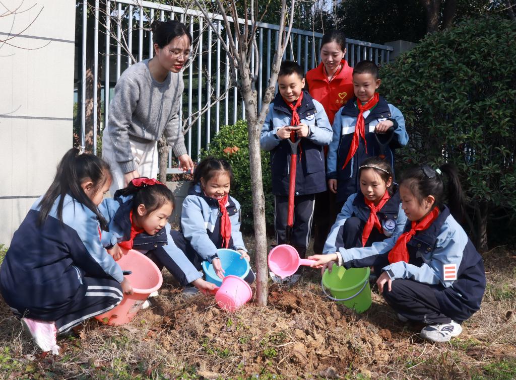 Murid-murid mengambil bahagian dalam acara menanam pokok bersama guru dan sukarelawan di sebuah sekolah rendah di Wuhan, provinsi Hubei, tengah China, 11 Mac 2026. (Foto oleh Zhao Jun/Xinhua)