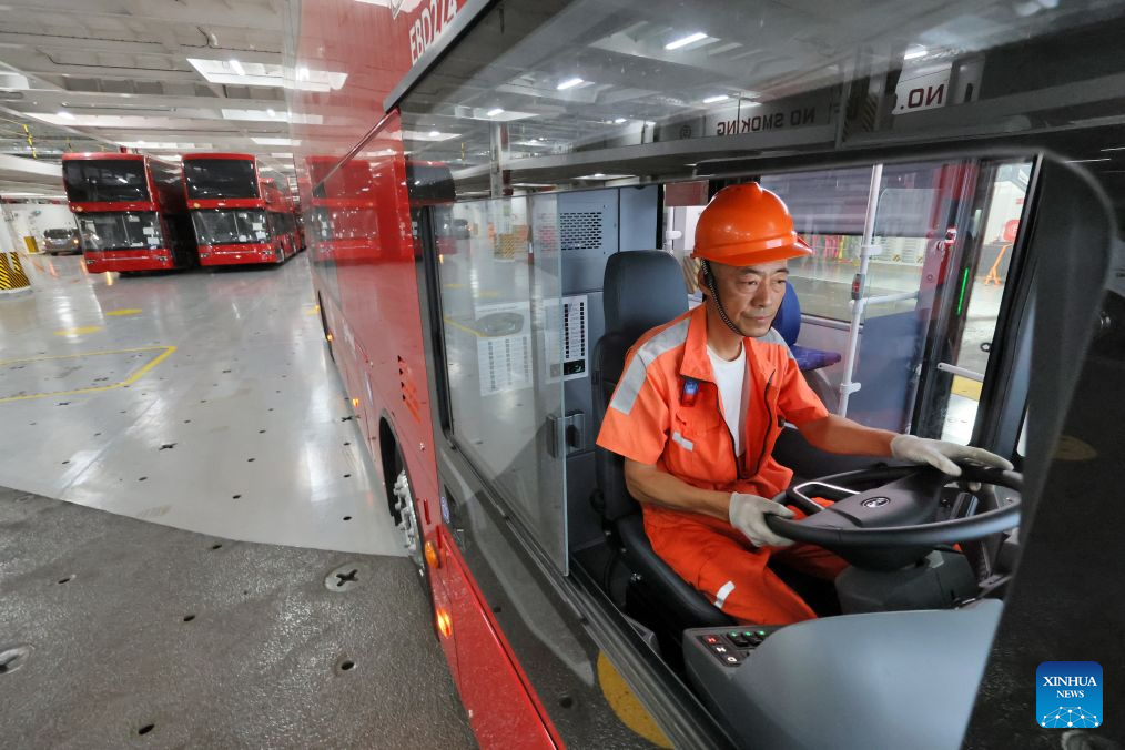 Seorang pemandu meletakkan bas dua tingkat elektrik buatan domestik ke dek pengangkut kenderaan di Pelabuhan Yantai, provinsi Shandong, timur China, 5 Julai 2026. (Foto oleh Tang Ke/Xinhua)