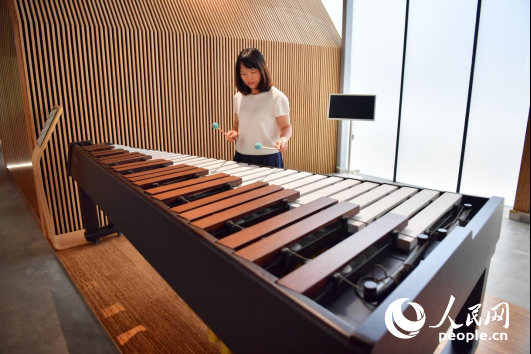 Wartawan sedang cuba bermain piano tiub buluh. (People’s Daily Online/Shi Yu)