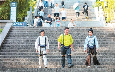 Pelancong memakai alat bantuan eksorangka ketika menuruni tangga di kawasan pemandangan bandar Fuqing, Provinsi Fujian, tenggara China. (Foto oleh Xie Guiming)