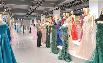 Zheng Jianbo, pengerusi Syarikat Chaozhou Best Fashion di Provinsi Guangdong, selatan China serang menyusun gaun malam di bilik pameran syarikatnya. (Foto oleh Huang Chunsheng)