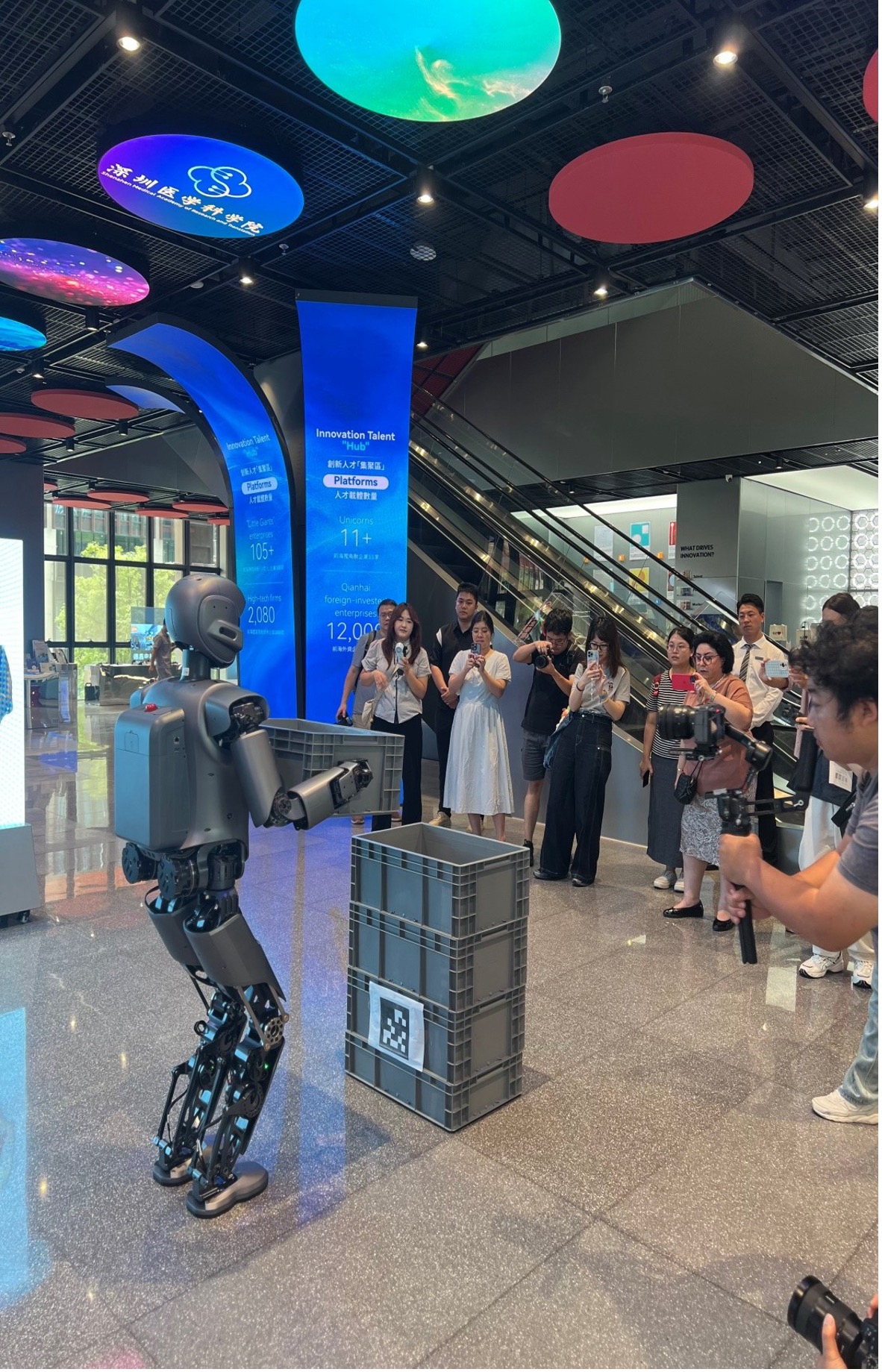 Wartawan menyaksikan satu robot humanoid yang membawa sebuah kotak di Ehub Belia Shenzhen-Hong Kong Qianhai pada 15 September 2025. (Oleh People’s Daily Online)
