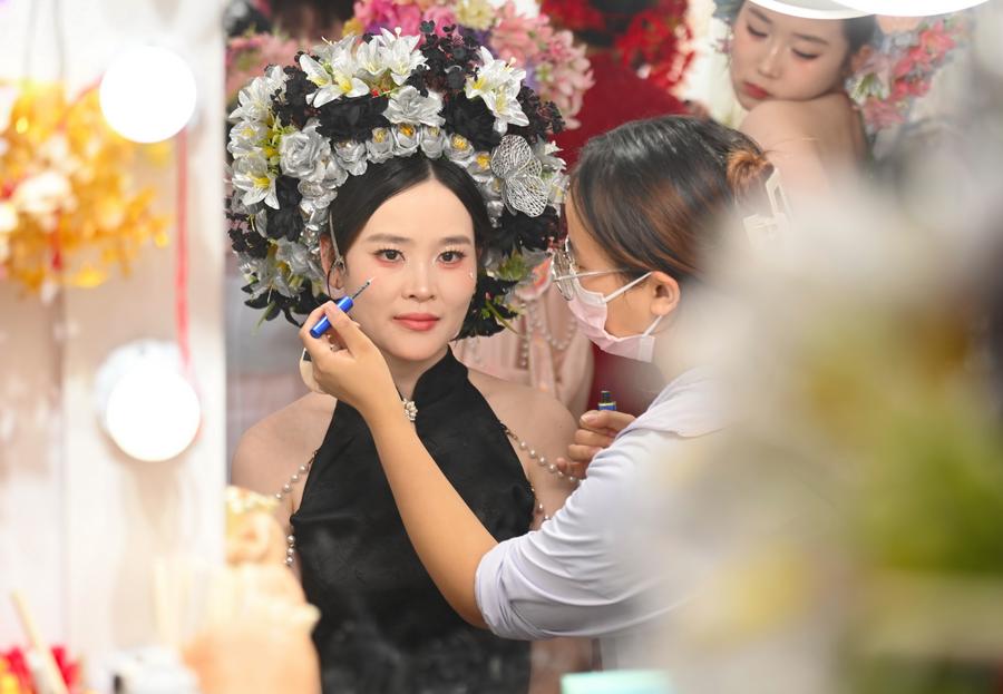 Seorang pelancong yang memakai hiasan kepala berbunga sedang ditatarias di sebuah studio fotografi di Kampung Xunpu, Bandar Quanzhou, Provinsi Fujian, tenggara China pada 18 Ogos 2025. Hiasan kepala berbunga Xunpu telah menjadi satu keistimewaan di Kampung Xunpu dan telah disenaraikan sebagai warisan budaya tidak ketara kebangsaan pada 2008. (Xinhua/Lin Shanchuan)