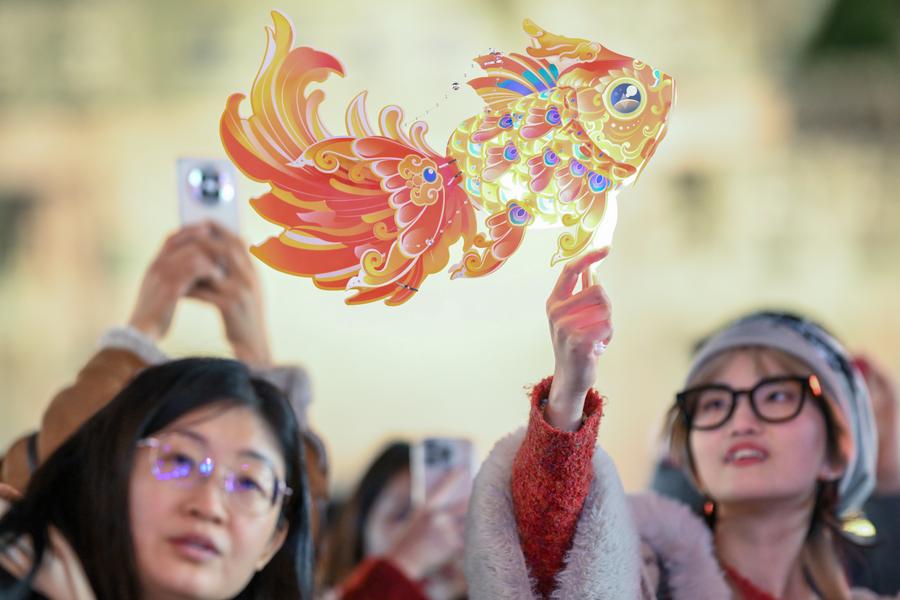 Seorang pengunjung memegang tanglung berbentuk ikan di kawasan pemandangan pekan purba Huishan di Bandar Wuxi, Provinsi Jiangsu di timur China pada 25 Januari 2025. (Xinhua/Wang Xuzhong)