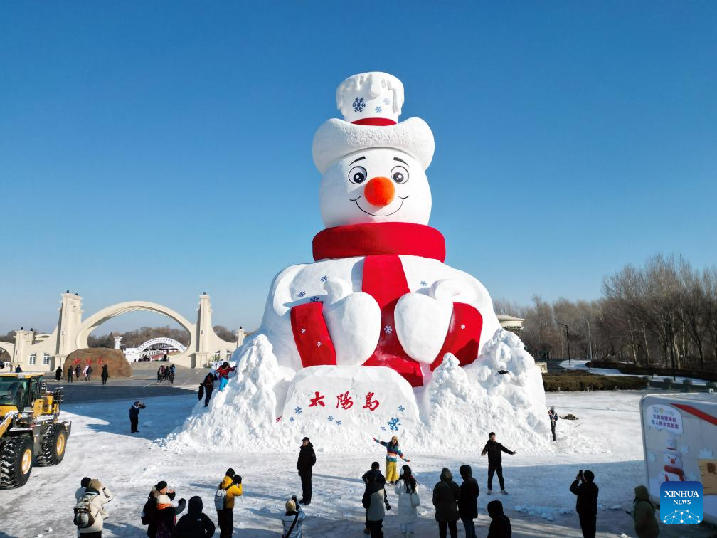 Foto dron bertarikh 9 Disember 2025 ini menunjukkan pelancong bergambar di depan “Mr. Snowman” di Sun Island, sebuah destinasi berpemandangan indah di provinsi Heilongjiang, timur laut China. (Foto oleh Liu Yang/Xinhua)