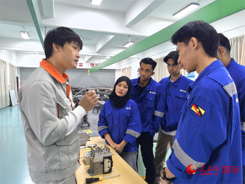 Gambar menunjukkan guru jurusan Operasi dan Penyelenggaraan Lokomotif Kolej Vokasional Kereta Api Liuzhou sedang menerangkan prinsip kerja peralatan kepada Hana (kiri kedua) dan rakan-rakannya. (People's Daily Online/Fu Huazhou)