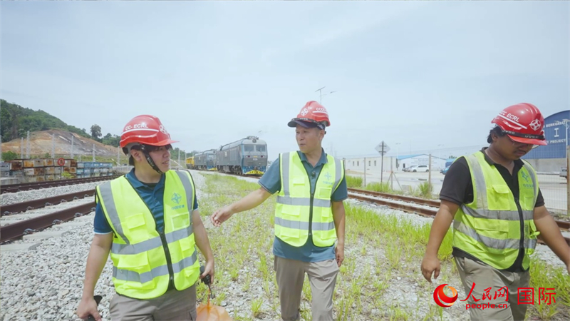 Gambar menunjukkan pelatih pembantu pemandu ECRL, Li U Wenn (kiri), sedang berbincang dengan guru pembimbingnya, Huang Mingyong (tengah). (People's Daily Online/Liu Ning)