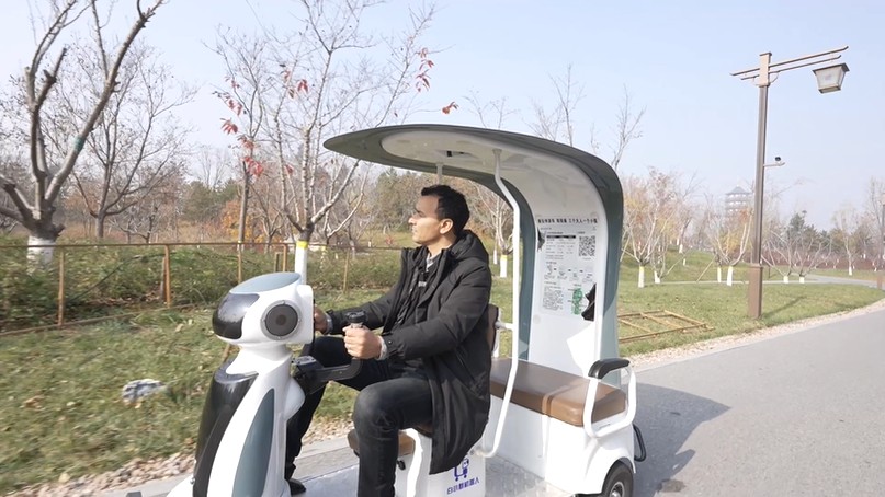 Seorang pelancong bersiar-siar menggunakan robot pemandu dan pengangkutan pintar di Taman Yuerong, Kawasan Baru Xiong’an, provinsi Hebei, utara China. (People's Daily Online/ Yuan Meng)