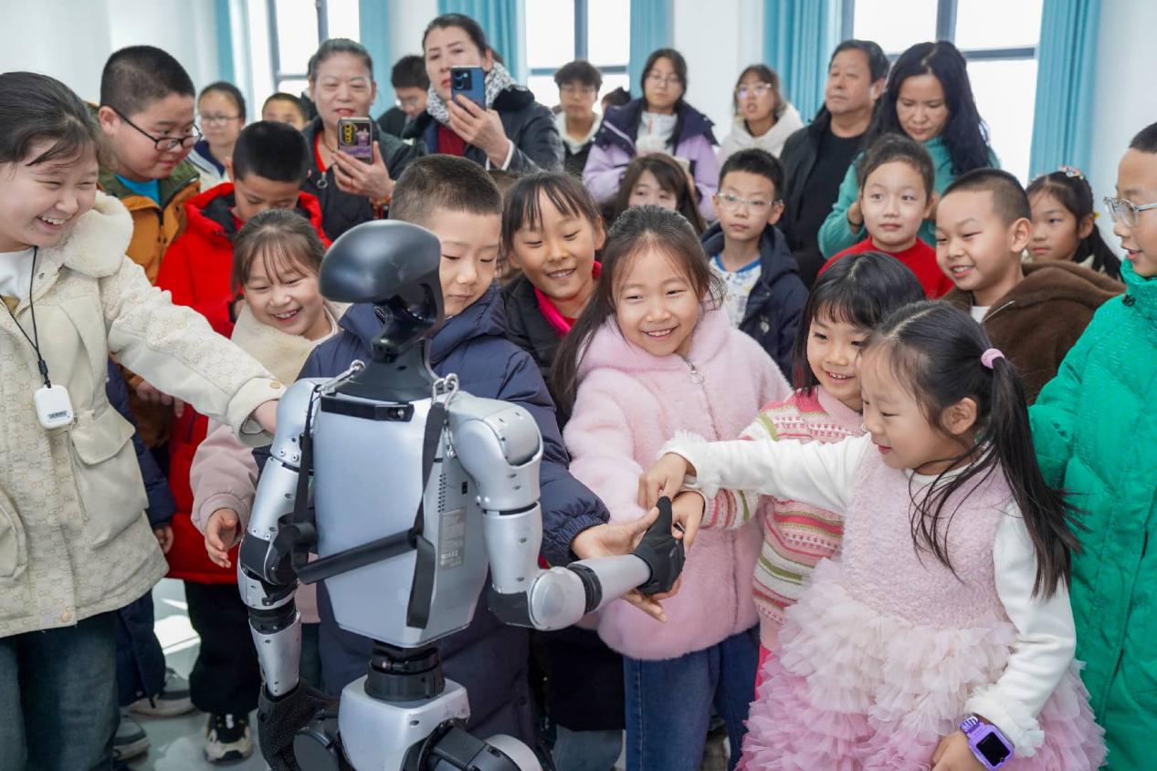 Sebuah robot berjabat tangan dengan kanak-kanak di Wusu, wilayah Xinjiang, barat laut China. (Foto/Li Renxi)