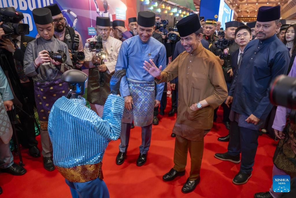 Sultan Haji Hassanal Bolkiah Mu'izzaddin Waddaulah (kedua dari kanan) berinteraksi dengan sebuah robot manusia dari China pada sambutan Hari Raya tradisional Brunei di Bandar Seri Begawan, 4 April 2026. (Jabatan Penerangan Jabatan Perdana Menteri Brunei menerusi Xinhua)