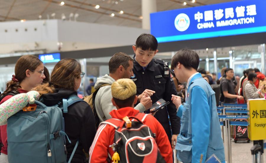 Seorang pegawai dari Pemeriksaan Sempadan Keluar dan Masuk Stesen Am Beijing memberikan maklumat kepada pelancong asing di Lapangan Terbang Antarabangsa Ibu Negara Beijing, 9 Januari 2026. (Foto oleh Zu Guobao/Xinhua)