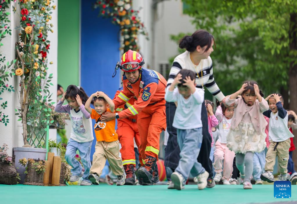 Kanak-kanak mengambil bahagian dalam latih tubi pemindahan kecemasan gempa bumi di bawah bimbingan bomba di sebuah tadika di kaunti autonomi Dong Yuping di bandar Tongren, provinsi Guizhou, barat daya China, 11 Mei 2026. (Hu Panxue/Xinhua)