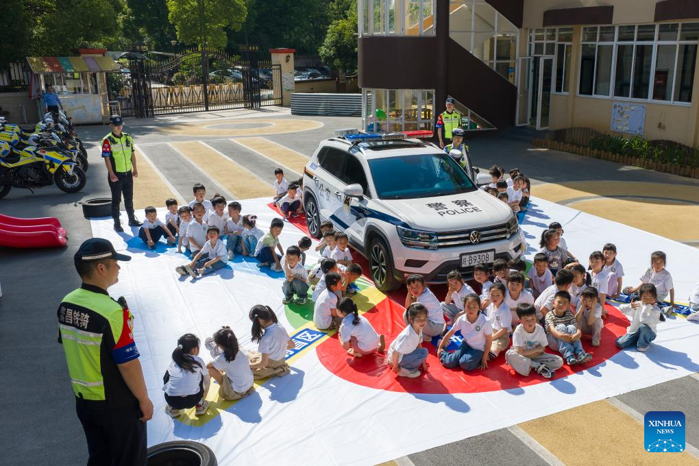 Foto dron pada 11 Mei 2026 menunjukkan pegawai polis mengajar kanak-kanak tentang titik buta kenderaan di sebuah tadika di Wuhu, provinsi Anhui, timur China. (Photo by Xiao Benxiang/Xinhua)