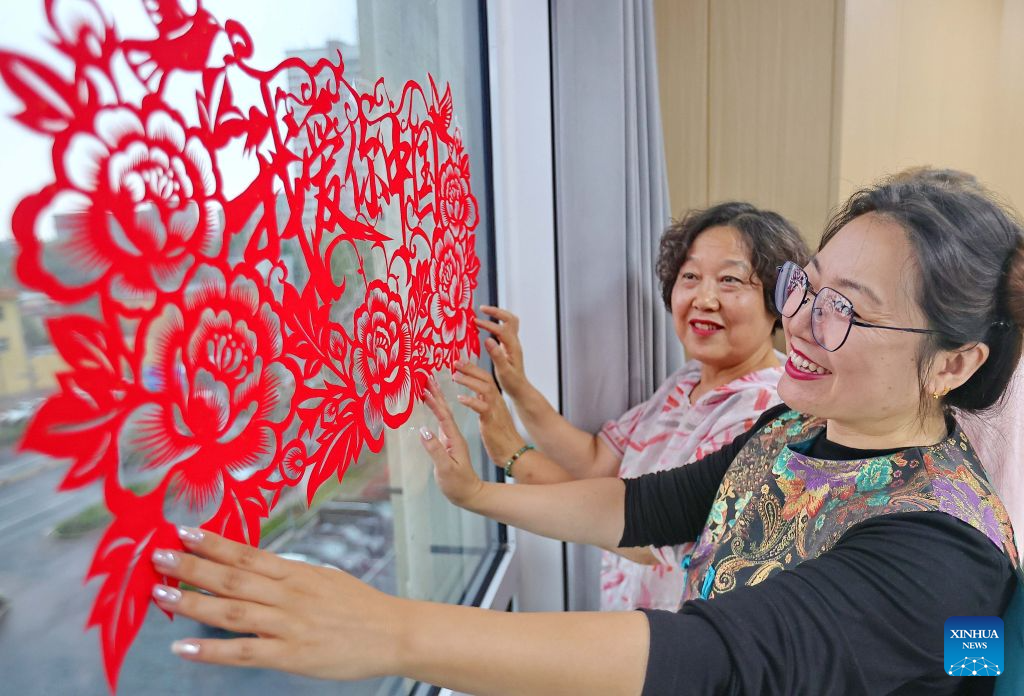 Wanita melekatkan hiasan guntingan kertas tradisional Cina pada tingkap kaca semasa aktiviti sambutan Hari Kebangsaan di daerah Haigang, Qinhuangdao, provinsi Hebei, utara China, 29 September 2026. Pelbagai aktiviti dianjurkan di merata negara sempena Hari Kebangsaan yang menjelang tiba. (Cao Jianxiong/Xinhua)