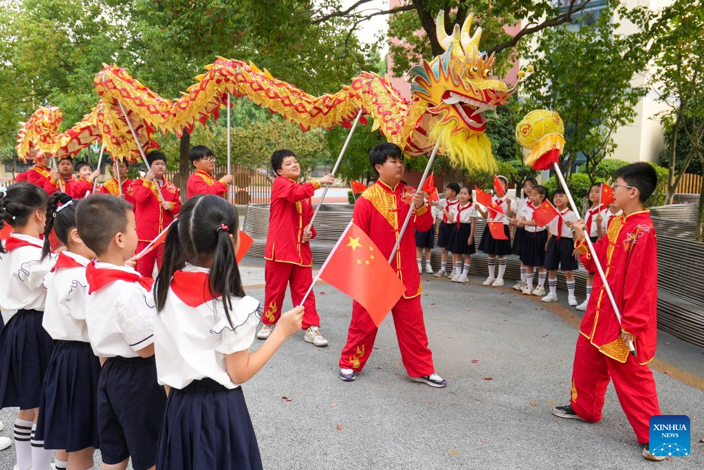 Pelajar menonton persembahan tarian naga di bandar Xinghua, provinsi Jiangsu, timur China, 29 September 2026. Pelbagai aktiviti dianjurkan di merata negara sempena Hari Kebangsaan yang menjelang tiba. (Zhou Shegen/Xinhua)