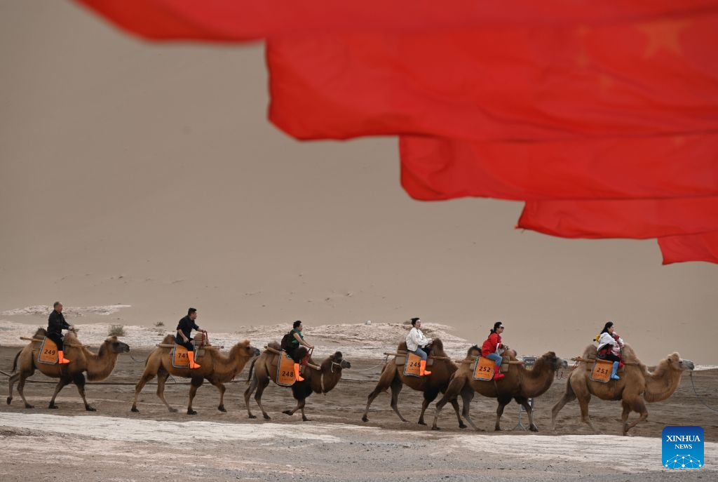 Pelancong menunggang unta di Kawasan Peranginan Gunung Mingsha dan Mata Air Bulan Sabit di Dunhuang, provinsi Gansu, barat laut China, 7 Oktober 2026. (Foto oleh Zhang Xiaoliang/Xinhua)