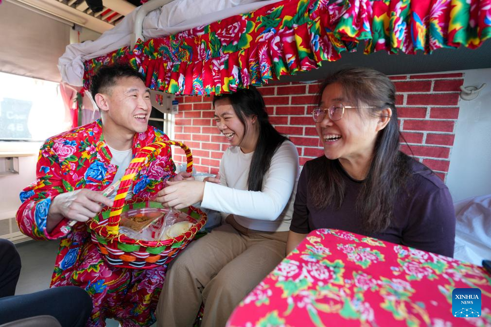 Seorang pelayan berpakaian tradisional membawakan penumpang penkek di sebuah “bazar dalam tren” di provinsi Heilongjiang, timur laut China, 4 Februari 2026. (Xinhua/Wang Song)