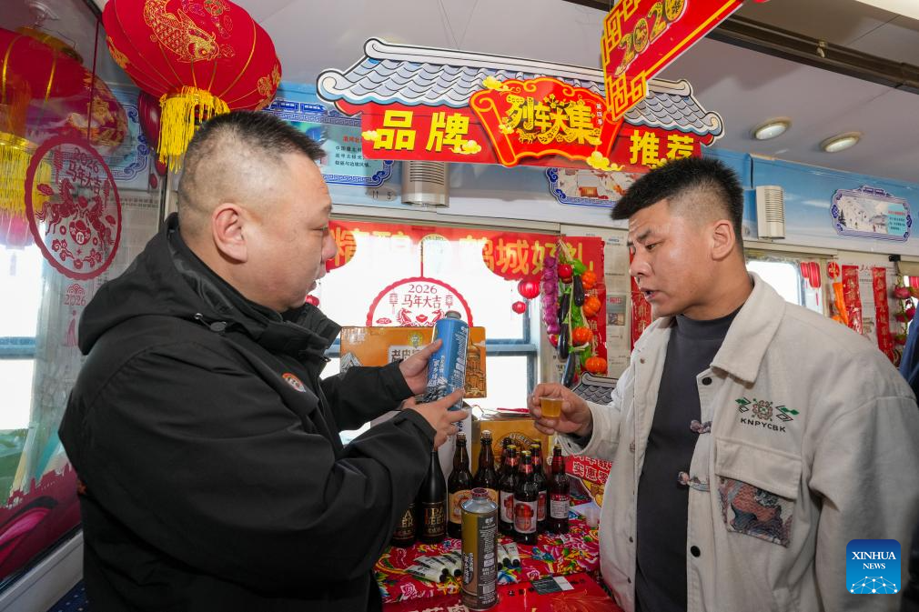 Seorang penjual (kiri) memperkenalkan keluaran istimewa tempatan kepada seorang pelancong di sebuah “bazar dalam tren” di provinsi Heilongjiang, timur laut China, 4 Februari 2026. (Xinhua/Wang Song)
