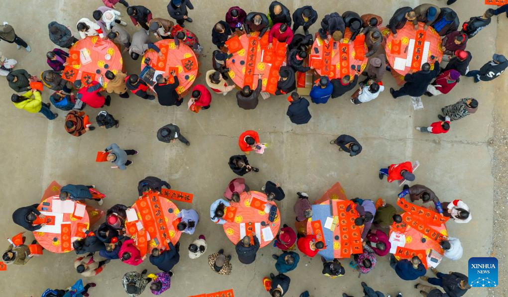 Foto dron bertarikh 4 Februari 2026 menunjukkan seorang jurukhat menulis kuplet dan karakter “Fu” (tuah) untuk orang ramai di sebuah pasar tani di pekan Jinglou, bandar Zhangshu, provinsi Jiangxi, timur China. (Zhou Liang/Xinhua)