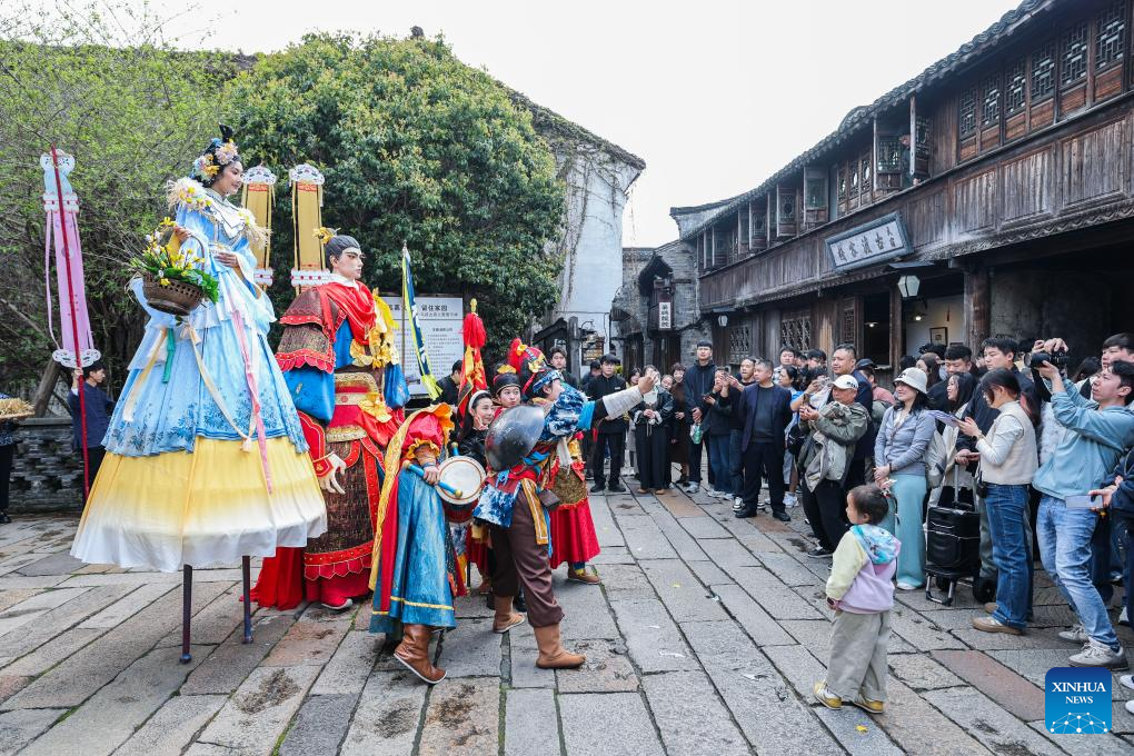 Peserta perarakan rakyat berinteraksi dengan pengunjung pada pesta rakyat di Wuzhen, bandar Tongxiang, provinsi Jiangsu, timur China, 1 April 2026. (Xinhua/Xu Yu)