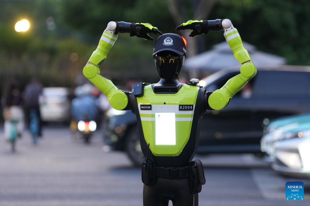 Sebuah robot pengurusan trafik pintar menunjukkan isyarat “hati” kepada pejalan kaki di satu persimpangan di kawasan komersial Hubin, Hangzhou, provinsi Zhejiang, timur China, 11 Mei 2026. (Xinhua/Huang Zongzhi)
