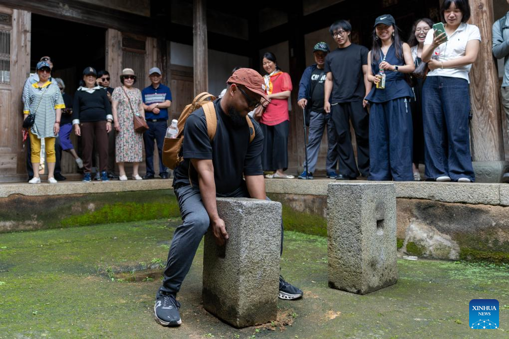 Seorang pengaudio siar dari Indonesia cuba mengangkat batu latihan seni mempertahankan diri tradisional etnik She yang beratnya sekitar 130kg di kampung Banyueli, kaunti Xiapu, bandar Ningde, provinsi Fujian, tenggara China, 10 Jun 2026. (Xinhua/Zhang Xiaoyu)